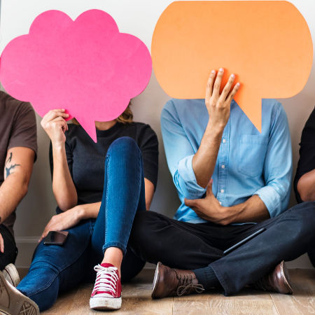 Man and woman holding conversation bubbles over their faces