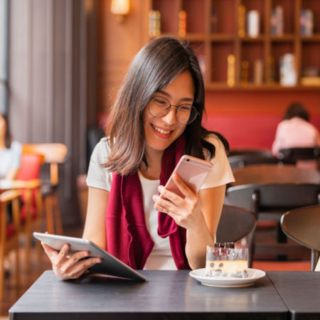Woman in cafe looking at phone and tablet