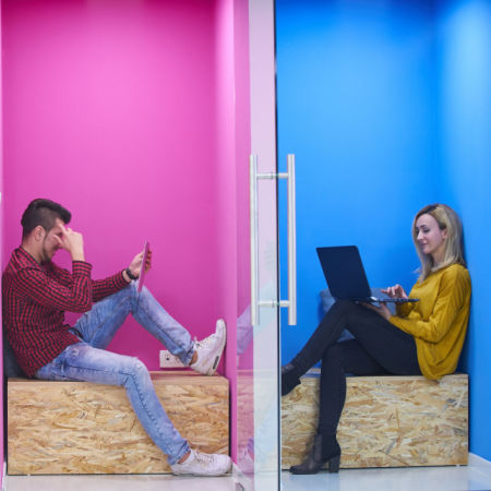 Man and woman on computes separated by wall
