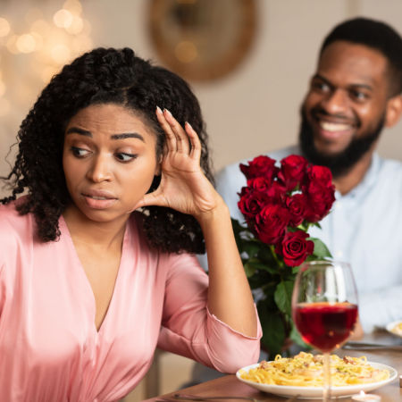 Disinterested woman on a bad first date with an eager man who is trying to give her flowers