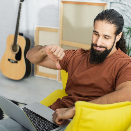 Man on a video speed date giving the thumbs-down sign to the computer camera