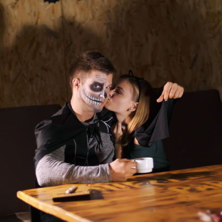 Man dressed as demon getting a kiss on the cheek from his date