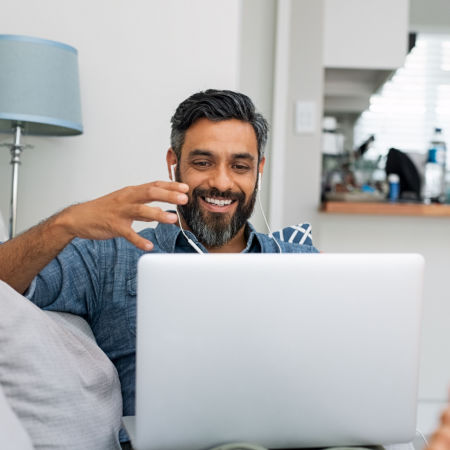 Man in his forties smiles at computer while on an online speed date