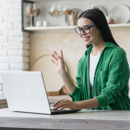 Woman smiling at computer as she flirts with her Couple.com online speed date