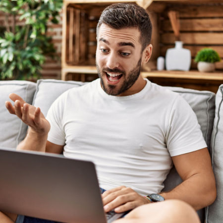 Man with computer on his lap. He gestures as he dominates the discussion on a Couple online speed date.