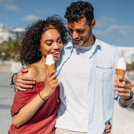 Man and woman on an outdoor date, walking and eating ice cream cone