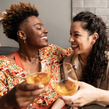 Single mother on a date with a new girlfriend; they are clinking glasses and smiling