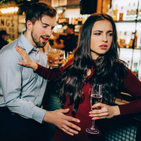 Drunk man on a first date grabs at his date while she pushes him away and looks annoyed