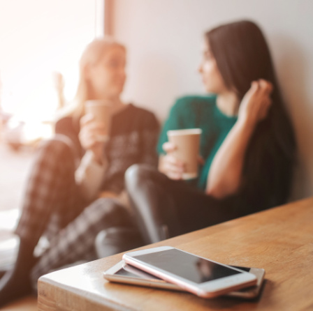 Two women on an "unplugged" coffee date. In the foreground are their phones, turned off and set aside.  