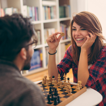 Man and woman on an old-school date without devices. They sit playing chess.