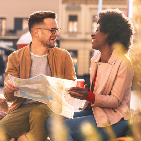 Smiling man and woman on an "unplugged date." They look at a paper map as they plan their walk through the city.