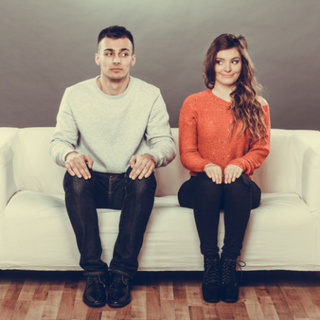 Man and woman sitting on couch on first date looking nervous and scared
