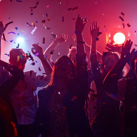 Crowd of people in a party with confetti falling from the ceilng